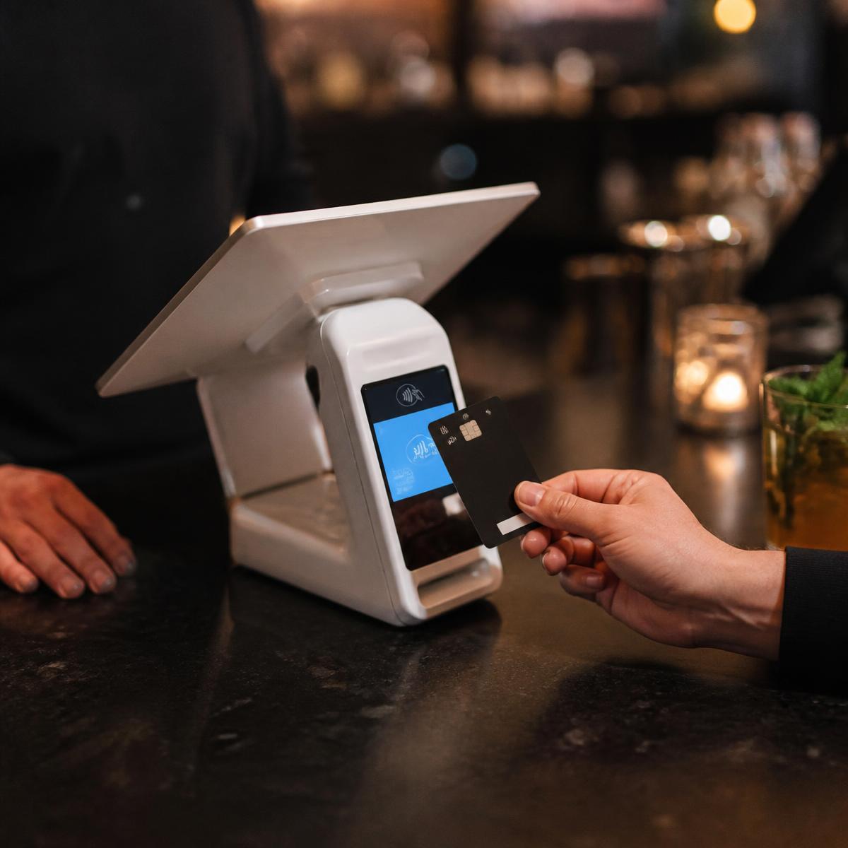 Customer tapping a card on a modern restaurant point-of-sale terminal
